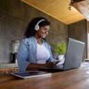 Mujer afroamericana trabajando en casa en su laptop y usando auriculares para una videoconferencia