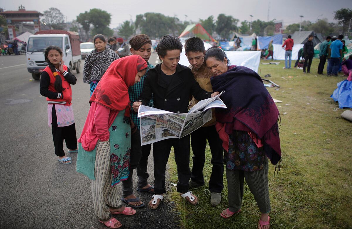 Los supervivientes del terremoto de Nepal leen el periódico en un campamento de Katmandú. (AP)