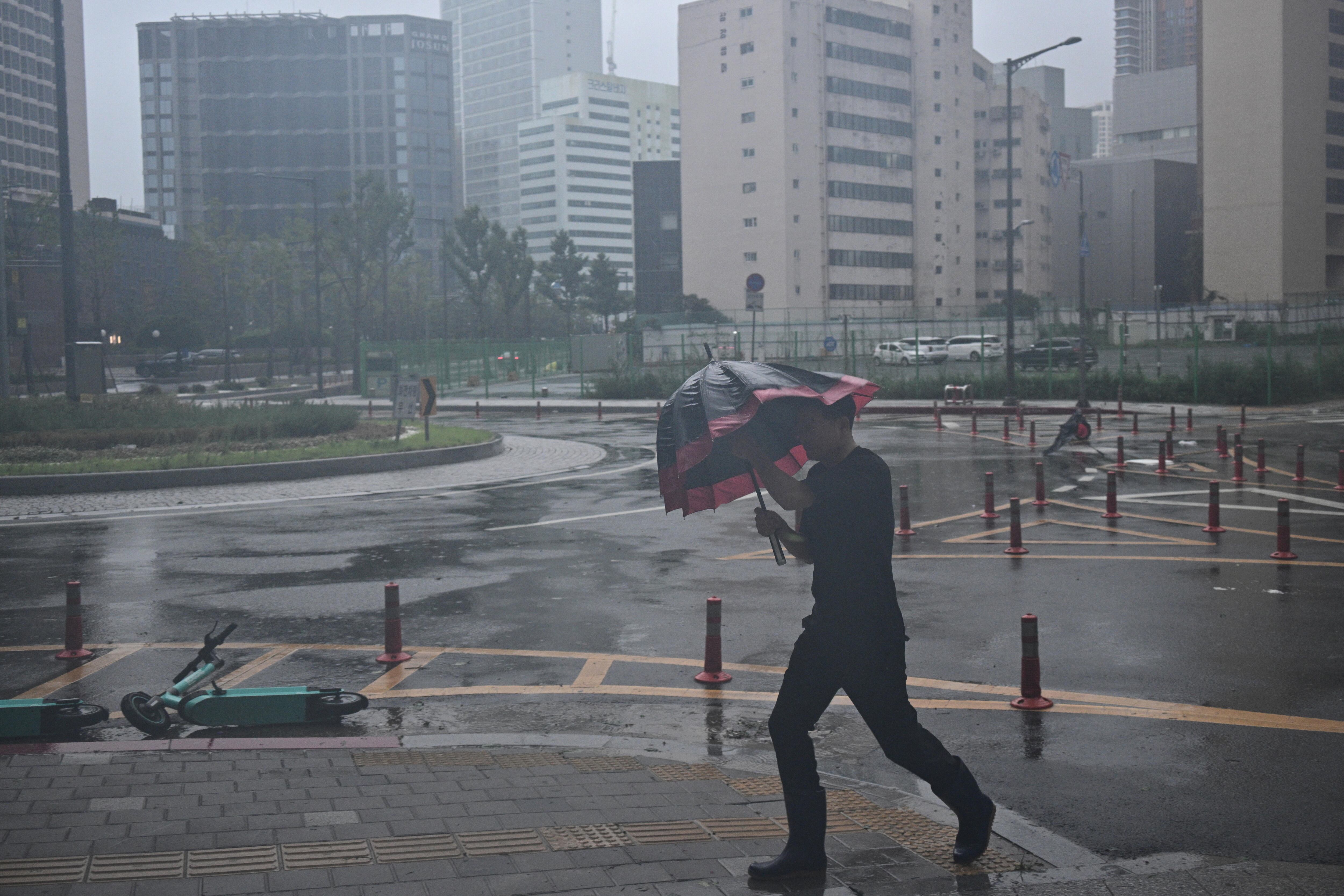 Un hombre intenta cubrirse con una sombrilla de las fuertes lluvias en Corea del Sur.