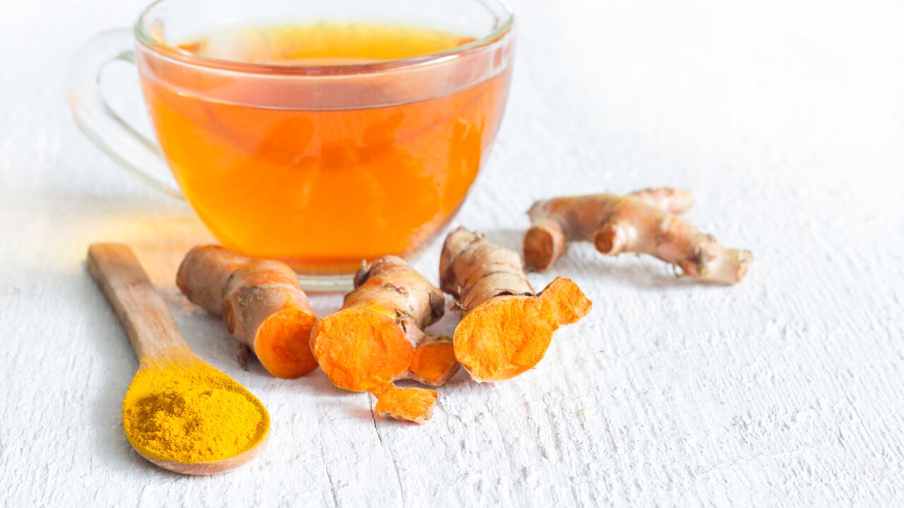 Raw roots of tumeric and tea on white planks detox concept closeup