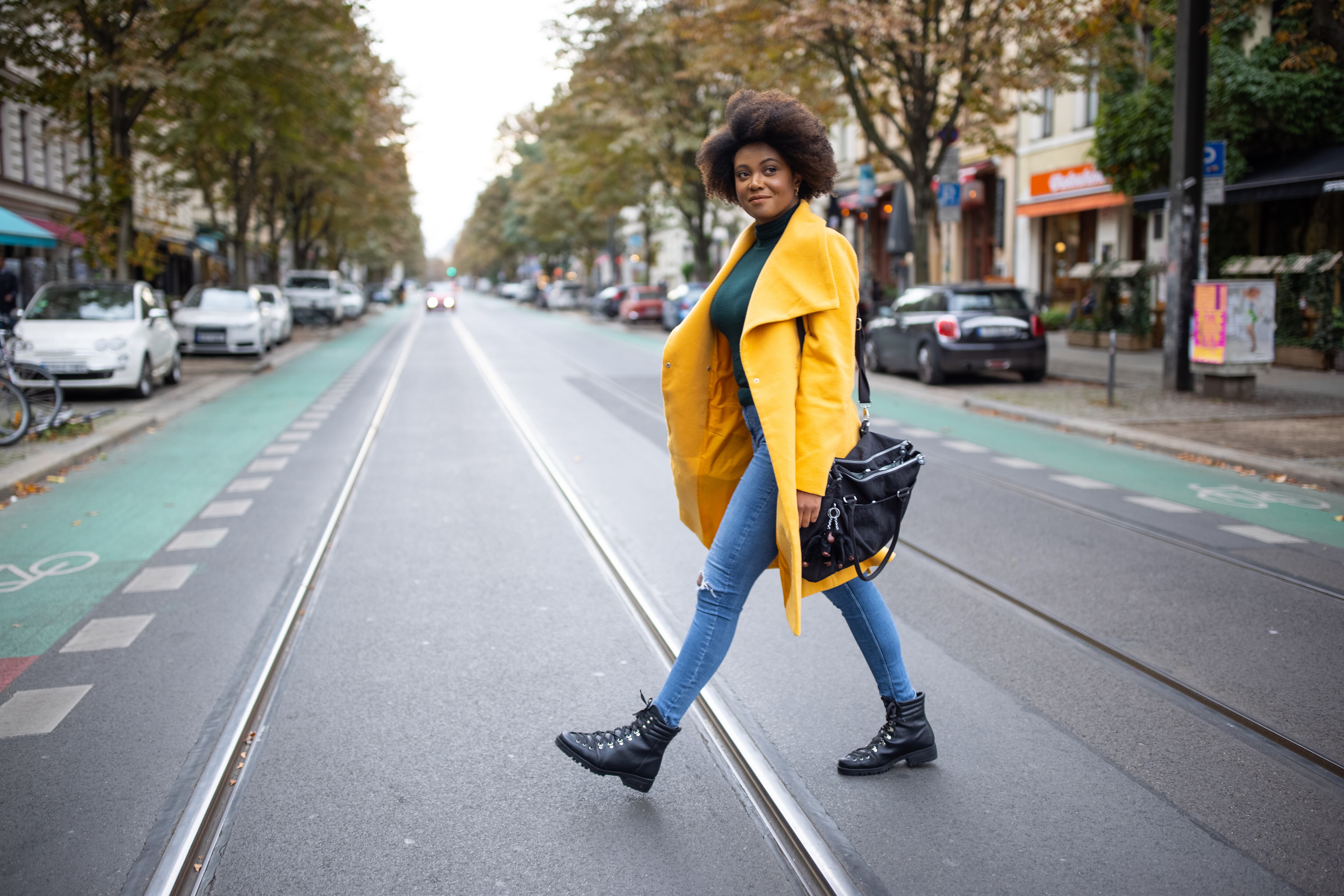 Full length of a woman crossing road. Female in casuals walking across the city street.