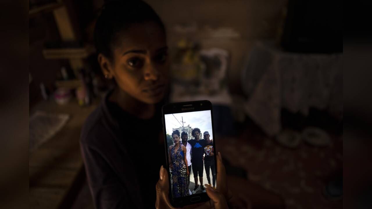 María Carla Milán Ramos muestra una foto en su teléfono de su esposo con sus hermanos, quienes están en prisión acusados de participar en protestas contra el gobierno en julio del año pasado, en su casa del barrio La Güinera en La Habana, Cuba, el miércoles 19 de enero de 2022. (AP Foto/Ramón Espinosa)