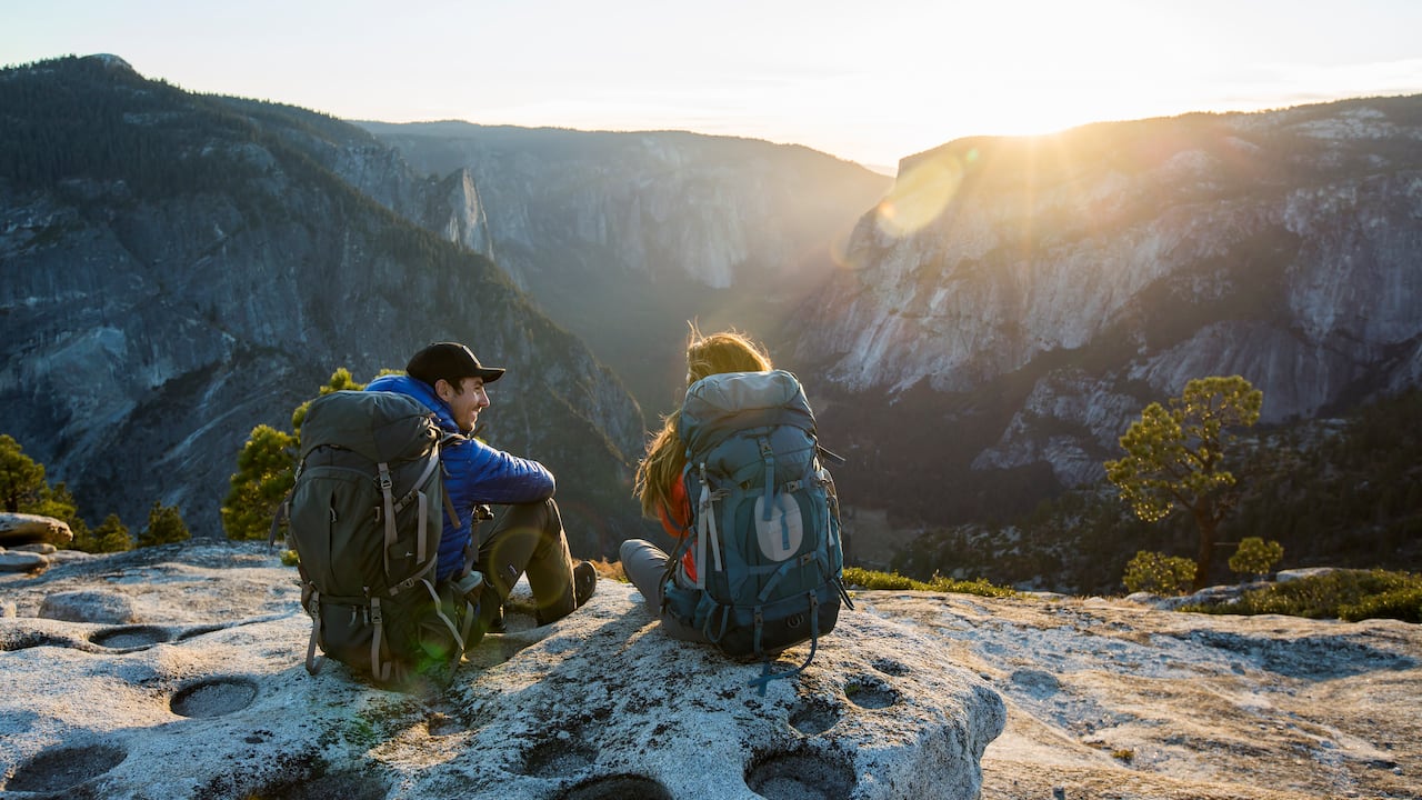 Una pareja sentada en una repisa mientras viajaba con mochila en el valle de Yosemite.