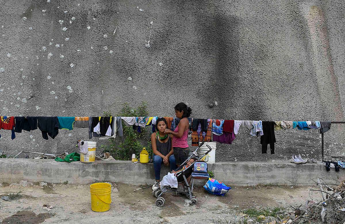 Las varillas de contención del túnel sirven de tendedero para que estas mujeres sequen su ropa después de lavarla en la cuenta donde se acomula una gran cantidad de agua, no potable. Foto: Matias Delacroix / AP.