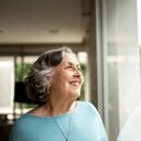 Senior woman looking through window at home