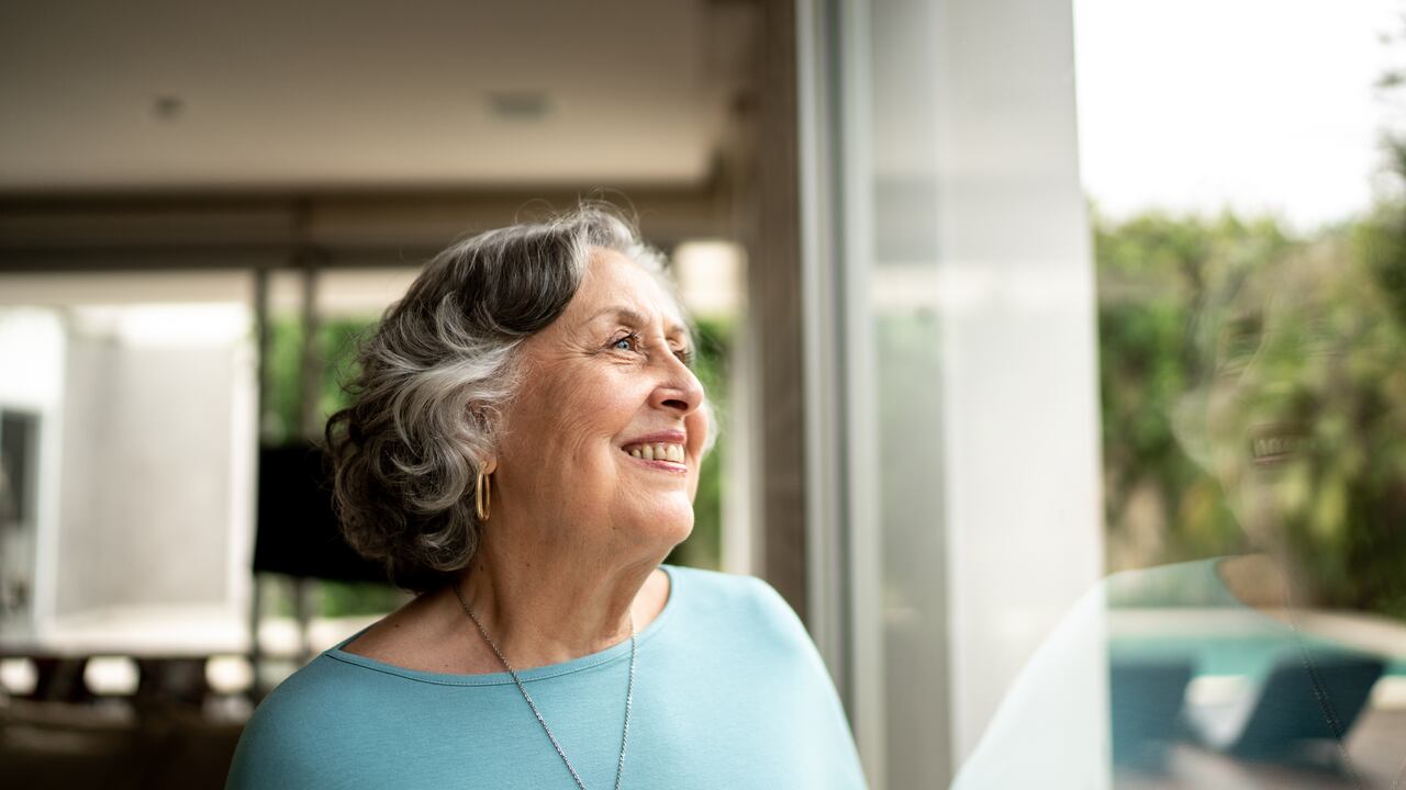 Senior woman looking through window at home