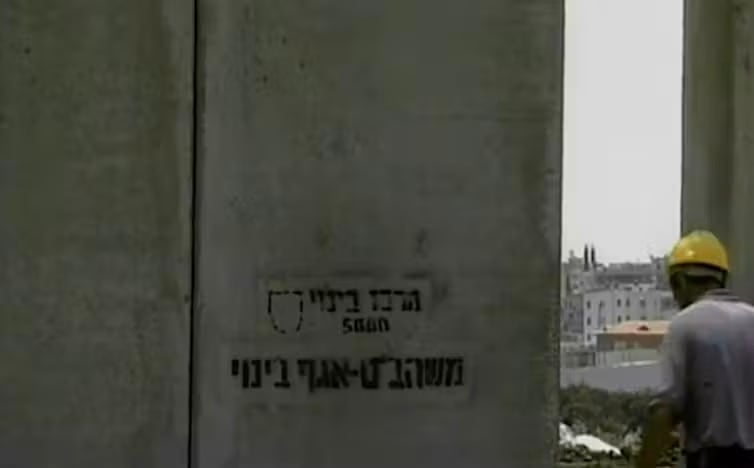 Un fotograma del documental de 2004 Wall muestra el momento en que se termina de construir un tramo de la barrera de Cisjordania. Down The Rabbit Hole/YouTube