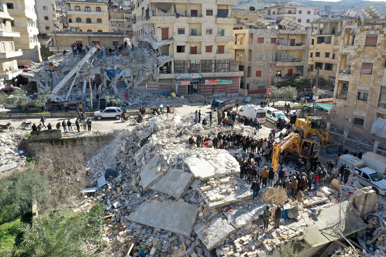 An aerial picture shows rescuers searching the rubble of buildings for casualties and survivors in the village of Salqin in Syria's rebel-held northwestern Idlib province at the border with Turkey following an earthquake, on February 7, 2023. (Photo by Omar HAJ KADOUR / AFP)