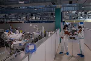 Los músicos Albert Skuratov, derecha, y Samuel Palomino, segundo a la derecha, interpretan un mini concierto de Mozart para pacientes con COVID-19 organizado por la Fundación Músicos por la Salud en la unidad de cuidados intensivos del Hospital Enfermera Isabel Zendal en Madrid, España, el jueves 11 de marzo , 2021. (Foto AP / Bernat Armangue)