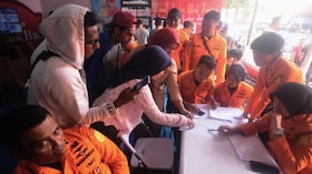 Gente busca nombres de sus familiares en una lista de pasajeros tras el naufragio de un ferri con mal tiempo en el mar de Java.