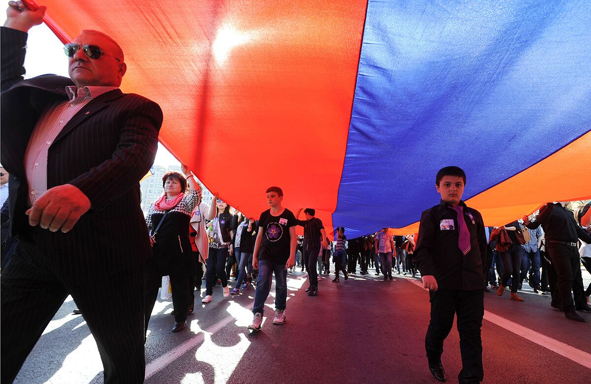 Los representantes de los armenios que viven en Polonia cargan una bandera gigante de Armenia mientras marchan hacia la embajada turca para conmemorar el 100° aniversario del genocidio armenio en Varsovia, Polonia. (AP)