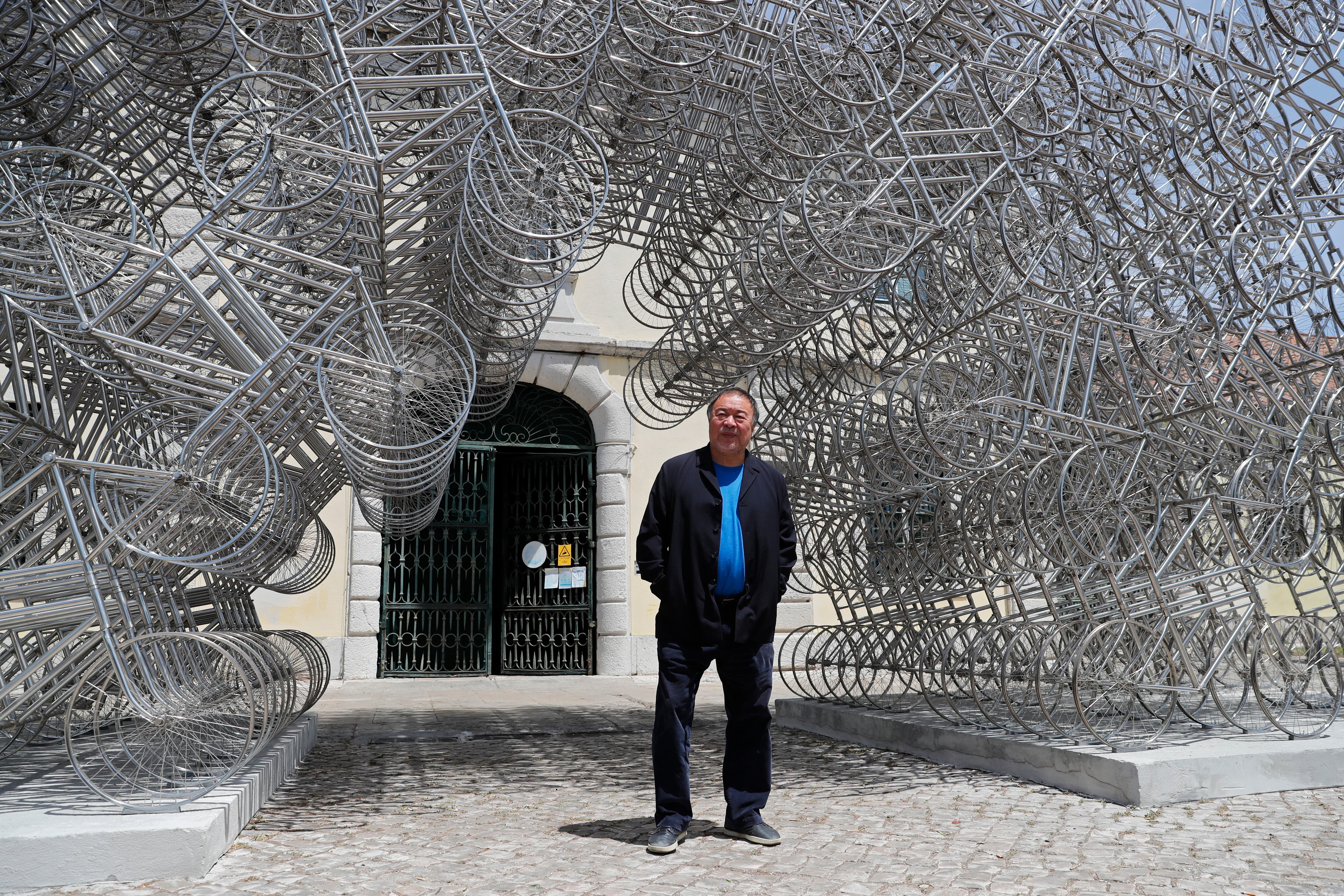 El artista chino disidente Ai Weiwei posa junto a su escultura "Forever Bicycles" durante un avance de prensa de su nueva exposición "Rapture" en Lisboa, el jueves 3 de junio de 2021. AP Photo/Armando Franca