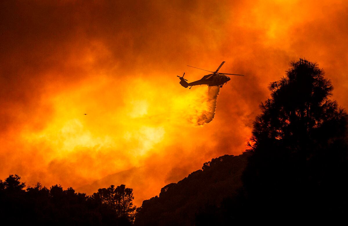 Un helicóptero arroja agua sobre el incendio del lago Hughes en el Bosque Nacional Ángeles, el miércoles 12 de agosto, al norte de Santa Clarita, California. Foto: Ringo H.W. Chiu / AP  