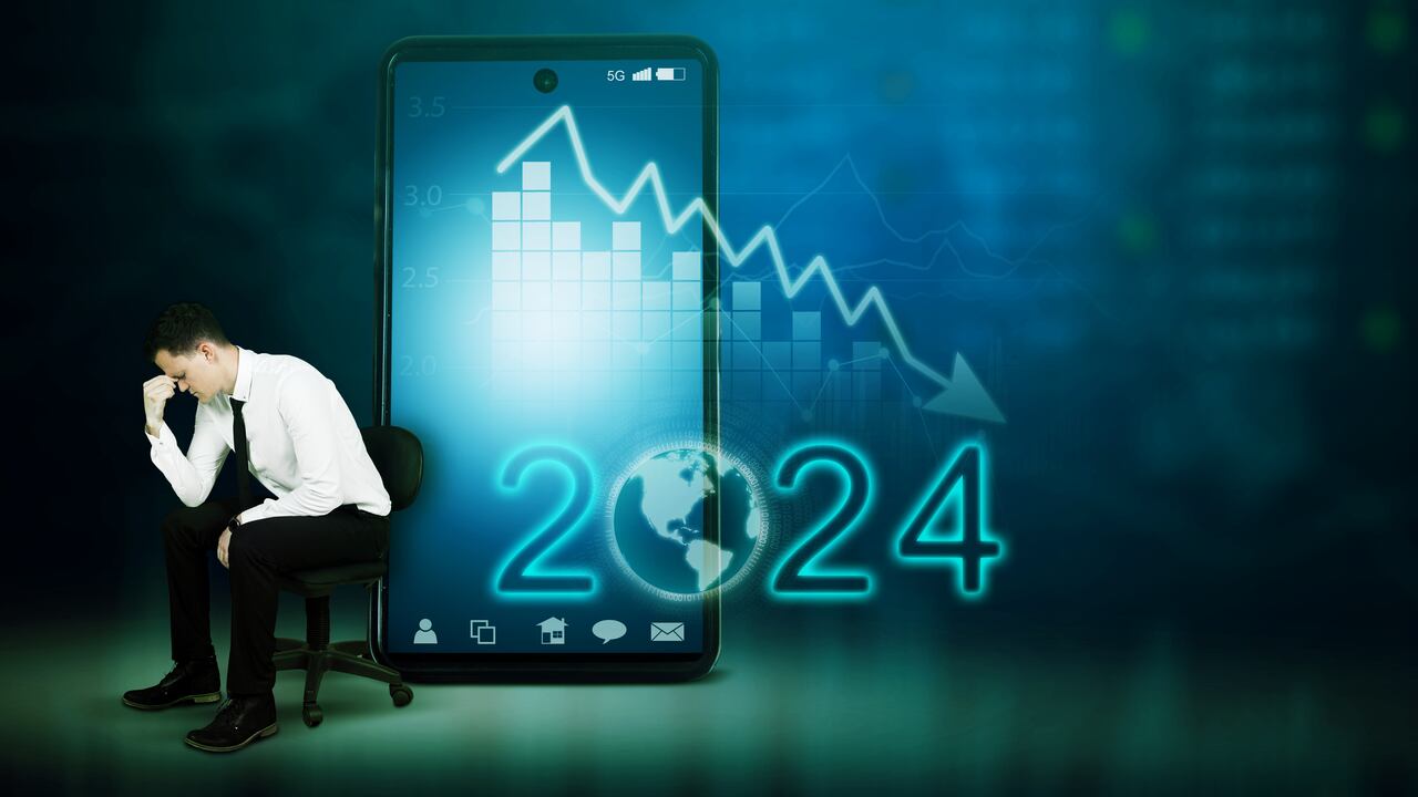 Stressed businessman sitting next to mobile phone with downtrend chart and number 2024
