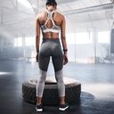 Shot of young women getting ready to lift a tyre in the gym