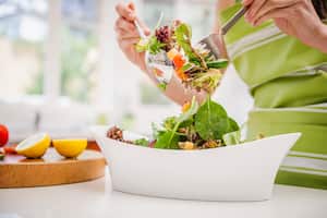 mujer hispana, tirar, ensalada, en, cocina doméstica