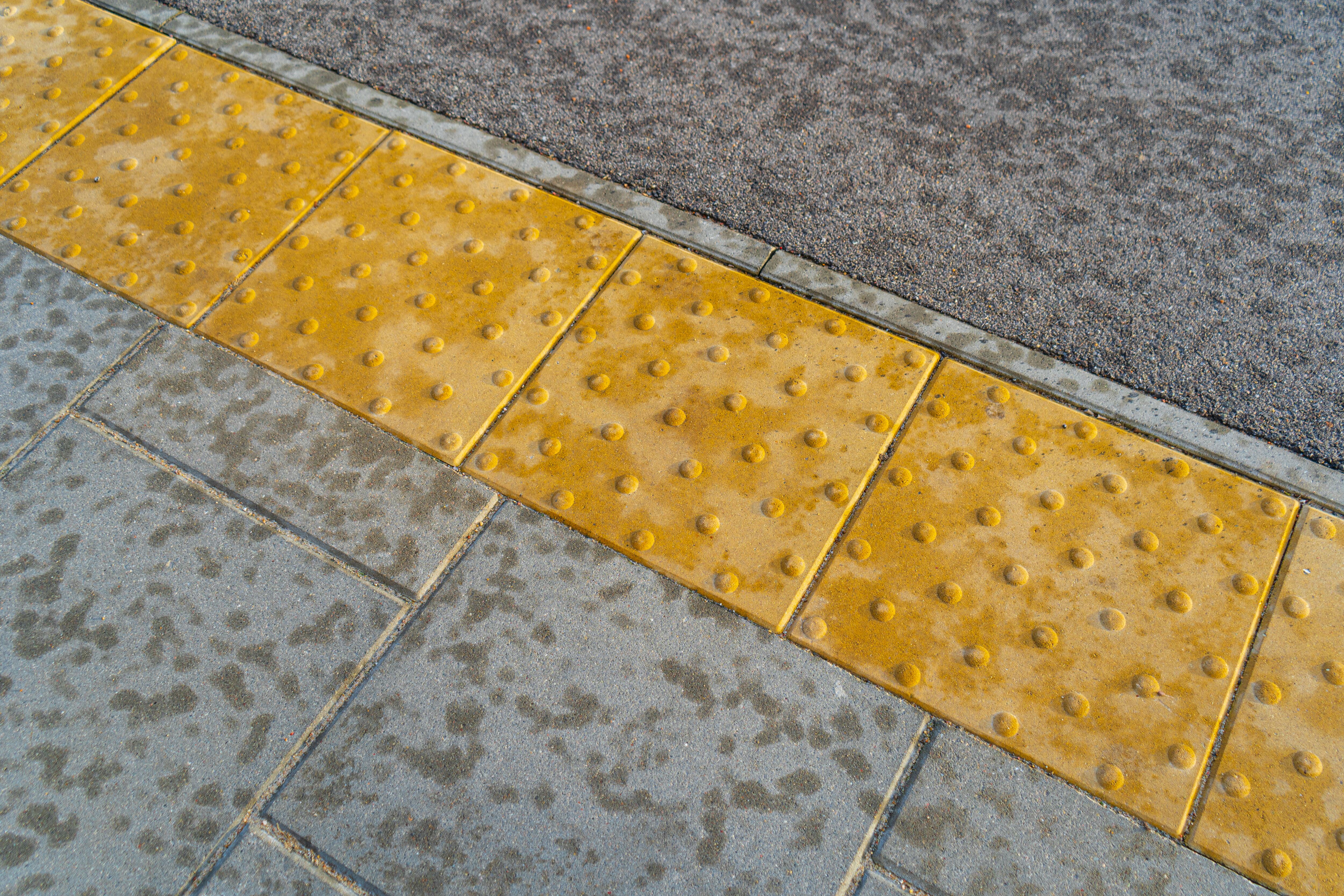 Pedestrian walking on tactile paving on footpath