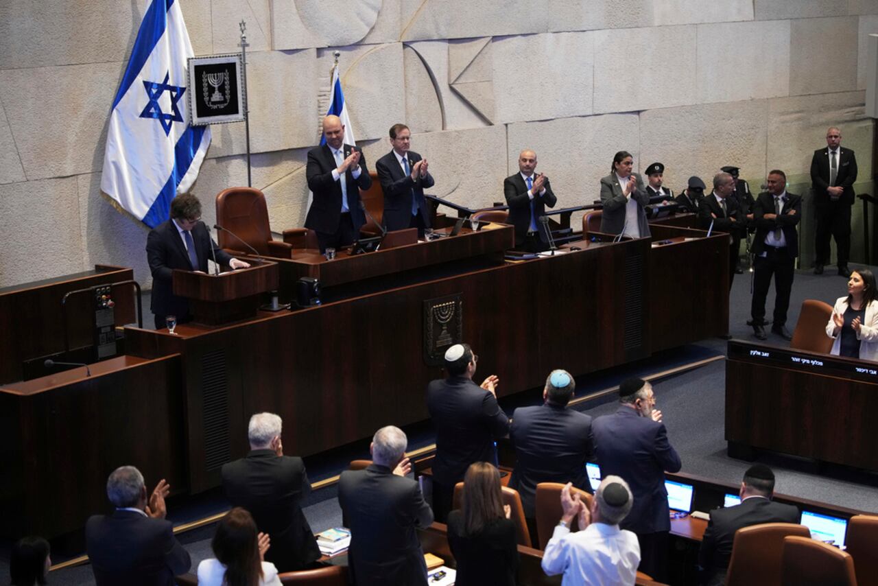 El presidente argentino, Javier Milei, a la izquierda en el podio, es aplaudido por los legisladores en la Knéset, el parlamento israelí, en Jerusalén, el miércoles 11 de junio de 2025. (Foto AP/Ohad Zwigenberg)