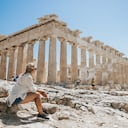 Mujer relajándose mientras mira el templo del Partenón contra el cielo despejado durante el día soleado