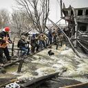Members of an Ukrainian civil defense unit pass new assault rifles to the opposite side of a blown up bridge on Kyiv�s northern front on March 1, 2022. - Satellite photos showed on March 1, 2022, a Russian convoy stretching for dozens of kilometers and advancing slowly toward the Ukrainian capital : according to the Ukrainian general staff, Moscow is gathering its forces for an assault on Kiev and other major cities while international retaliatory measures against Russia continued to accumulate. (Photo by ARIS MESSINIS / AFP)