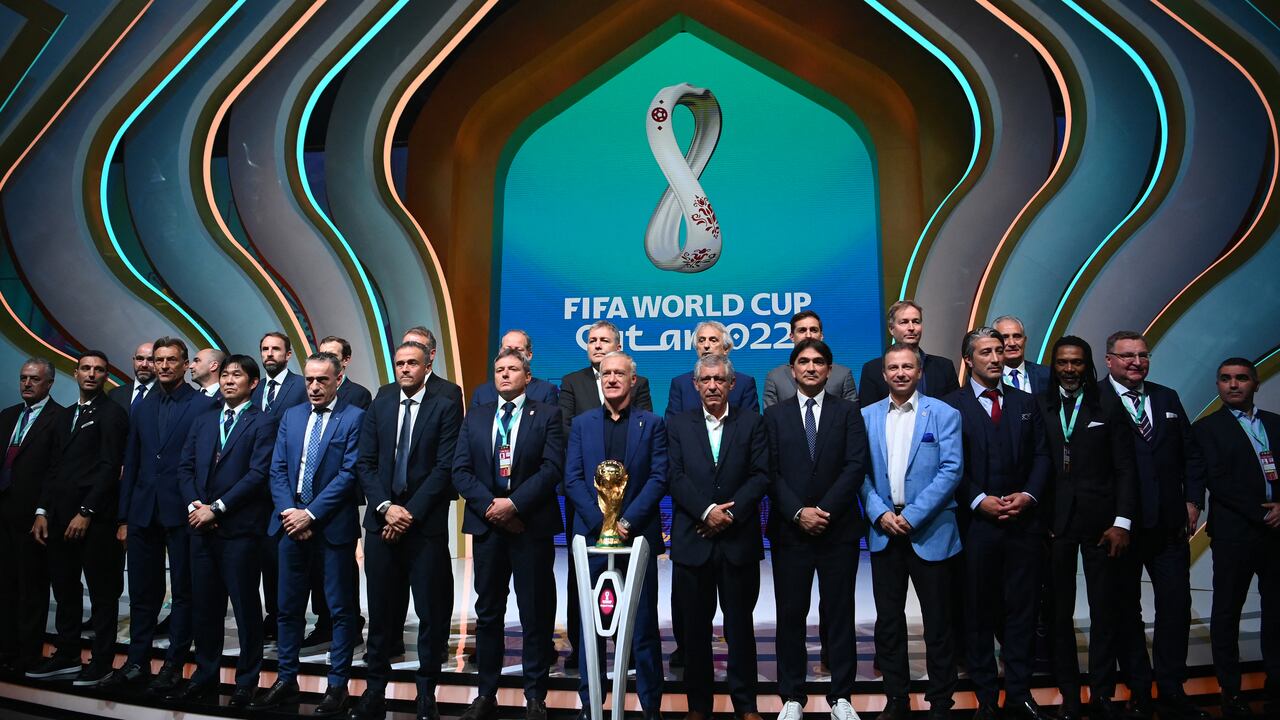 Los entrenadores posan frente al trofeo de la Copa del Mundo durante el sorteo de la Copa del Mundo de 2022 en Qatar en el Centro de Convenciones y Exposiciones de Doha el 1 de abril de 2022. (Photo by FRANCK FIFE / AFP)
