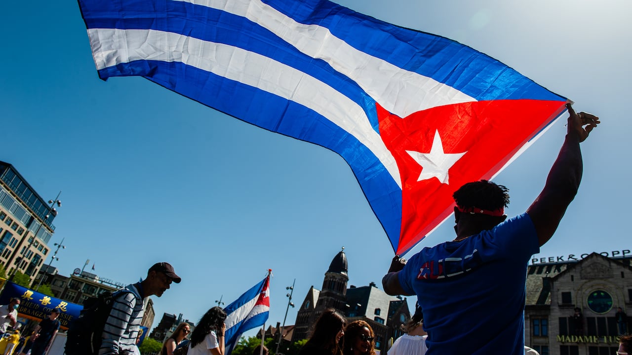 Un hombre sostiene una gran bandera cubana durante una manifestación en apoyo a Cuba.