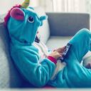 niñita disfrazada de unicornio relajándose con el móvil en el sofá de casa