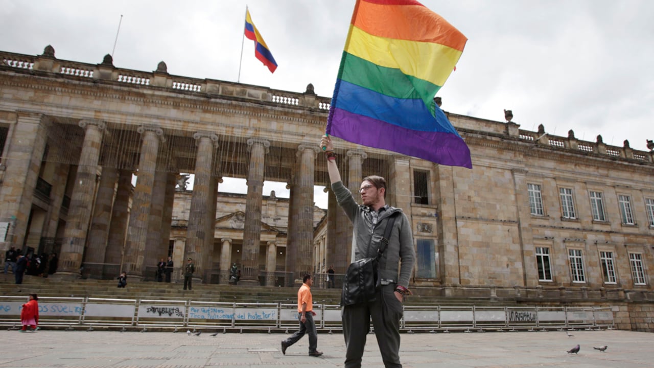 Un hombre sostiene una bandera de la comunidad LGBTI frente al Congreso de la República de Colombia.