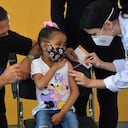 El gobernador de Sao Paulo, Joao Doria, mira a una niña que reacciona mientras recibe la primera dosis de la vacuna Pfizer-BioNTech contra el COVID-19, en el hospital Clínicas de Sao Paulo, Brasil, el 14 de enero de 2022.