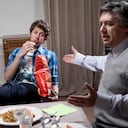 A disinterested teenager eating potato chips and being lectured to by his father.