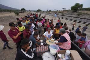 A group of nuns distribute food to migrants resting rest along the train tracks in Huehuetoca, Mexico, Friday, May 12, 2023, as they look to board a freight train heading north, the day after U.S. pandemic-related asylum restrictions called Title 42 were lifted. (AP Photo/Marco Ugarte)