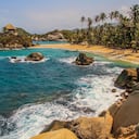 Hermosa playa tropical con el famoso monumento de una cabaña de playa y un océano azul con olas blancas, palmeras y bosque lluvioso en el Parque Nacional Tayrona, Colombia