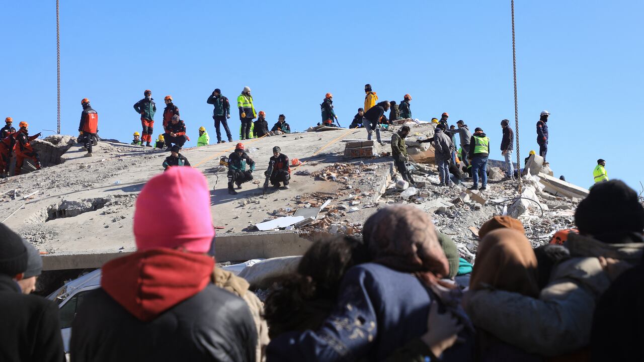 La gente observa cómo los rescatistas y los civiles buscan sobrevivientes bajo los escombros de los edificios derrumbados en Nurdagi, en el campo de Gaziantep, el 9 de febrero de 2023, tres días después de un terremoto mortal que azotó Turquía y Siria.(Photo by Zein Al RIFAI / AFP)