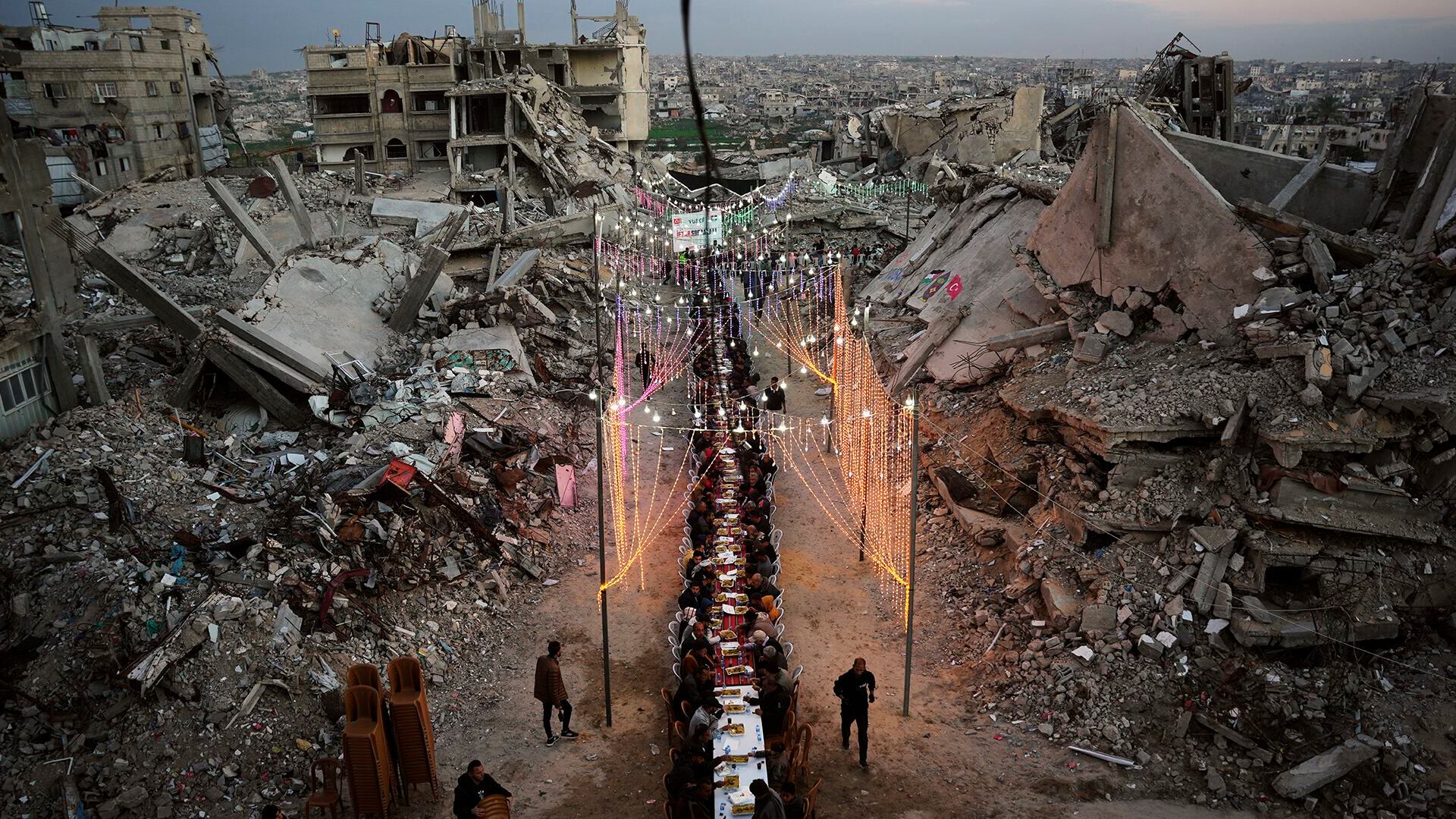 Palestinos se reúnen en torno a una larga mesa instalada entre los escombros de edificios destruidos para el iftar, la comida con la que se rompe el ayuno durante el Ramadán, en Khan Younis, Franja de Gaza, el 19 de febrero de 2026.