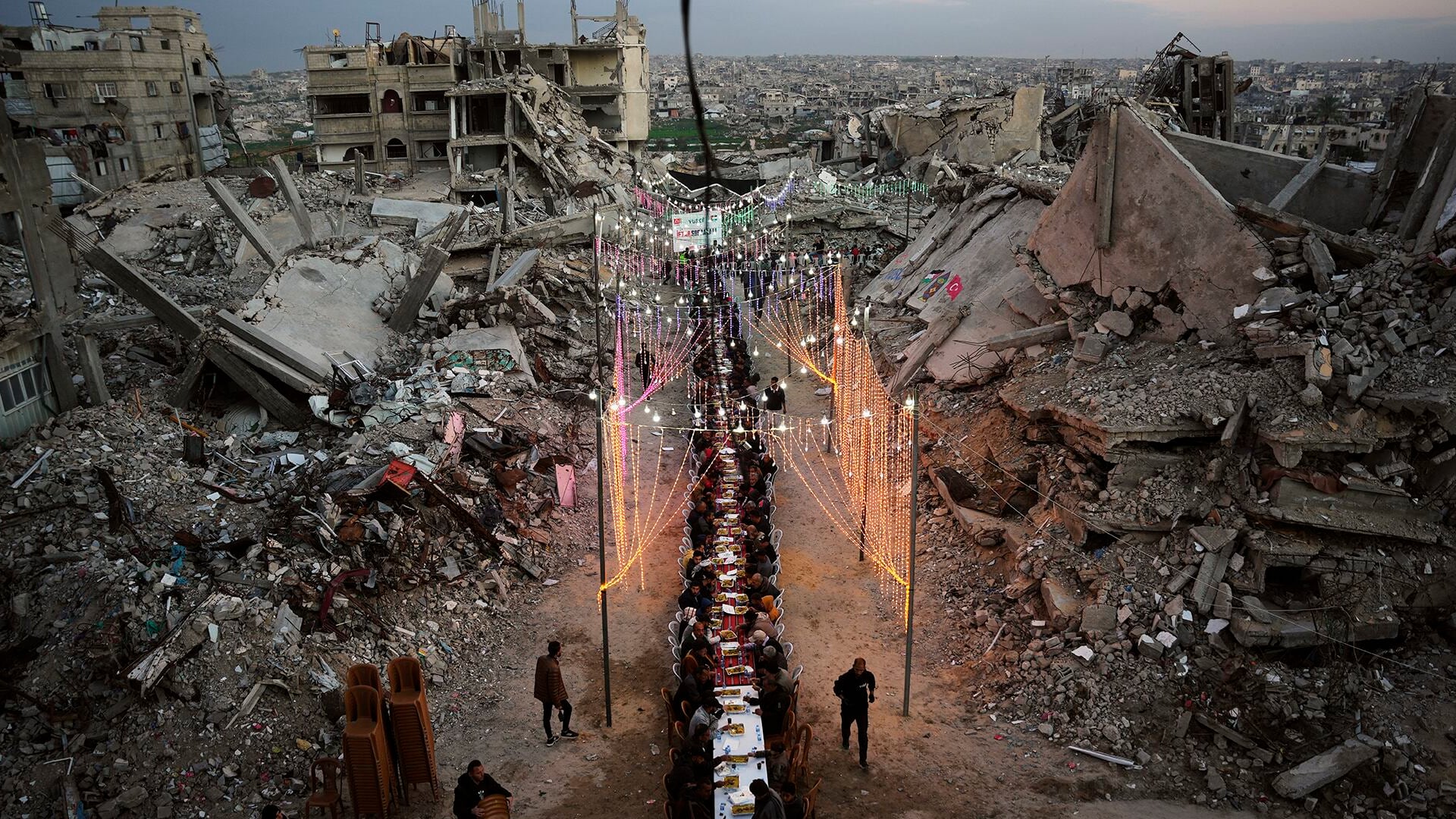 Palestinos se reúnen en torno a una larga mesa instalada entre los escombros de edificios destruidos para el iftar, la comida con la que se rompe el ayuno durante el Ramadán, en Khan Younis, Franja de Gaza, el 19 de febrero de 2026.