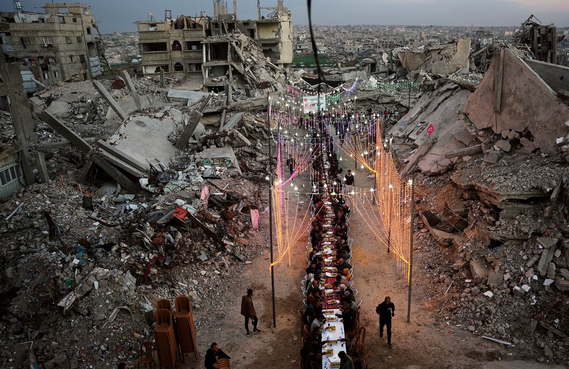 Palestinos se reúnen en torno a una larga mesa instalada entre los escombros de edificios destruidos para el iftar, la comida con la que se rompe el ayuno durante el Ramadán, en Khan Younis, Franja de Gaza, el 19 de febrero de 2026.