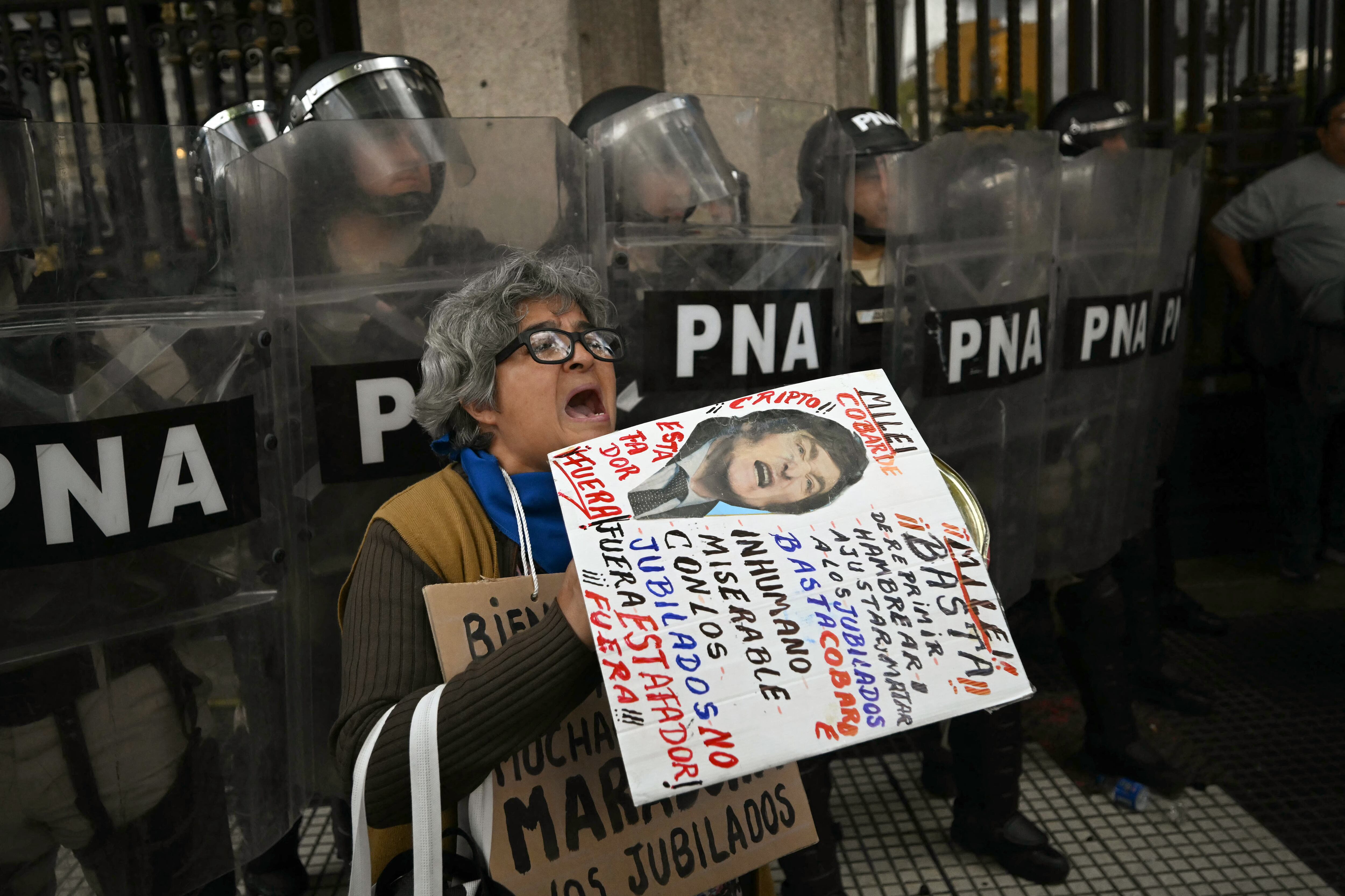 Una mujer grita consignas frente a la policía durante una protesta de jubilados, apoyada por hinchas de fútbol, contra el gobierno del presidente Javier Milei en Buenos Aires el 12 de marzo de 2025. (Foto de Luis ROBAYO / AFP)