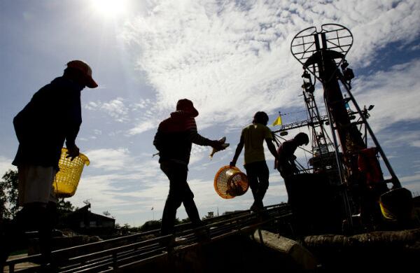 Trabajadores migrantes de Birmania vuelven a un barco con sus cestas después de un viaje de pesca en el Golfo de Tailandia. (AP)