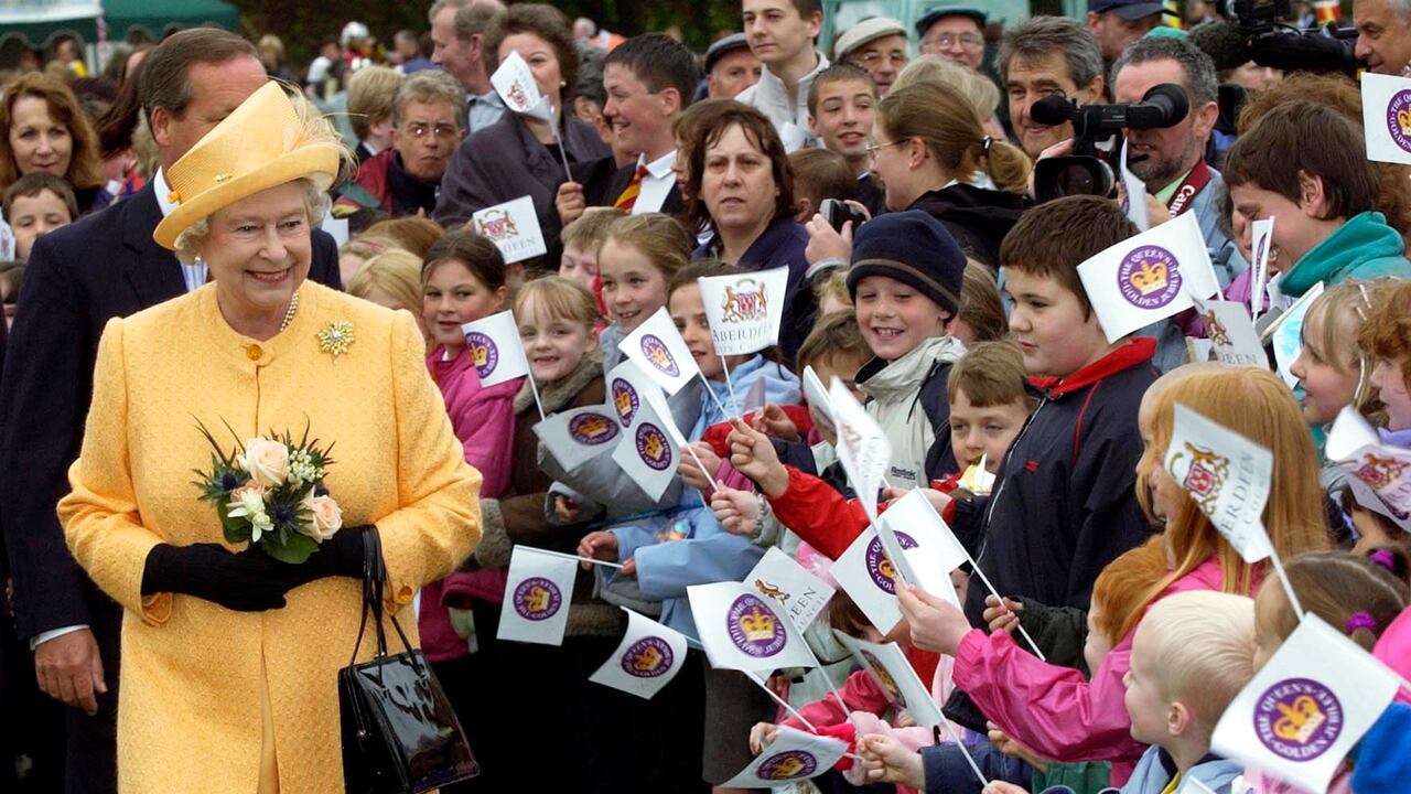 Su majestad se vale de su cartera para ganar espacio cuando alguien se le acerca más de lo deseable. Así lució en Aberdeen, durante su jubileo dorado en 2002.