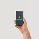 Hand holding smart phone with popular online text / call application "WhatsApp" logo on screen. Illustrative editorial image with copy space for text.