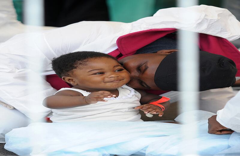 Un migrante, de los 700 que cruzaron el mediterráneo, besa un bebé luego de que descendieran del barco italiano 'Bettica' en Salerno, Sicilia. (AP/Francesco Pecoraro)