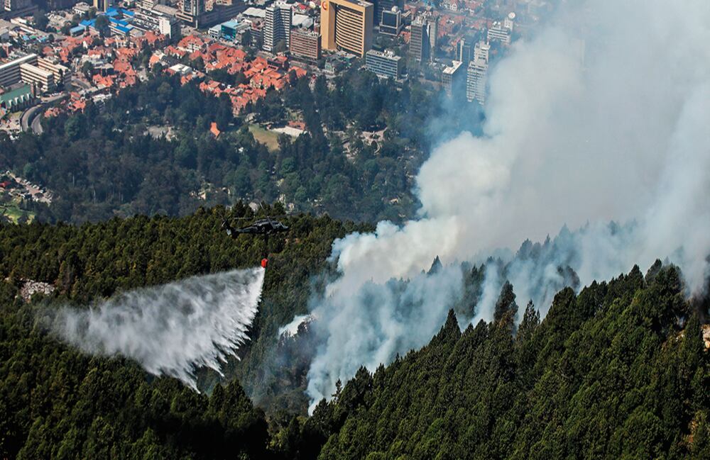  Helicópteros UH-60 Black Hawk descargan más de 800 galones de agua en los incendios. Los pinos se pierden en las columnas de humo. 