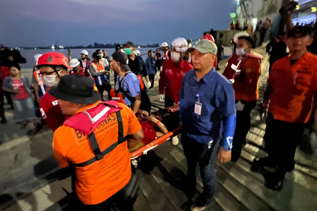 En esta fotografía tomada con un teléfono inteligente, los rescatistas transportan a un sobreviviente en una camilla después de que un ferri se hundiera debido al mal tiempo en el mar de Java.
