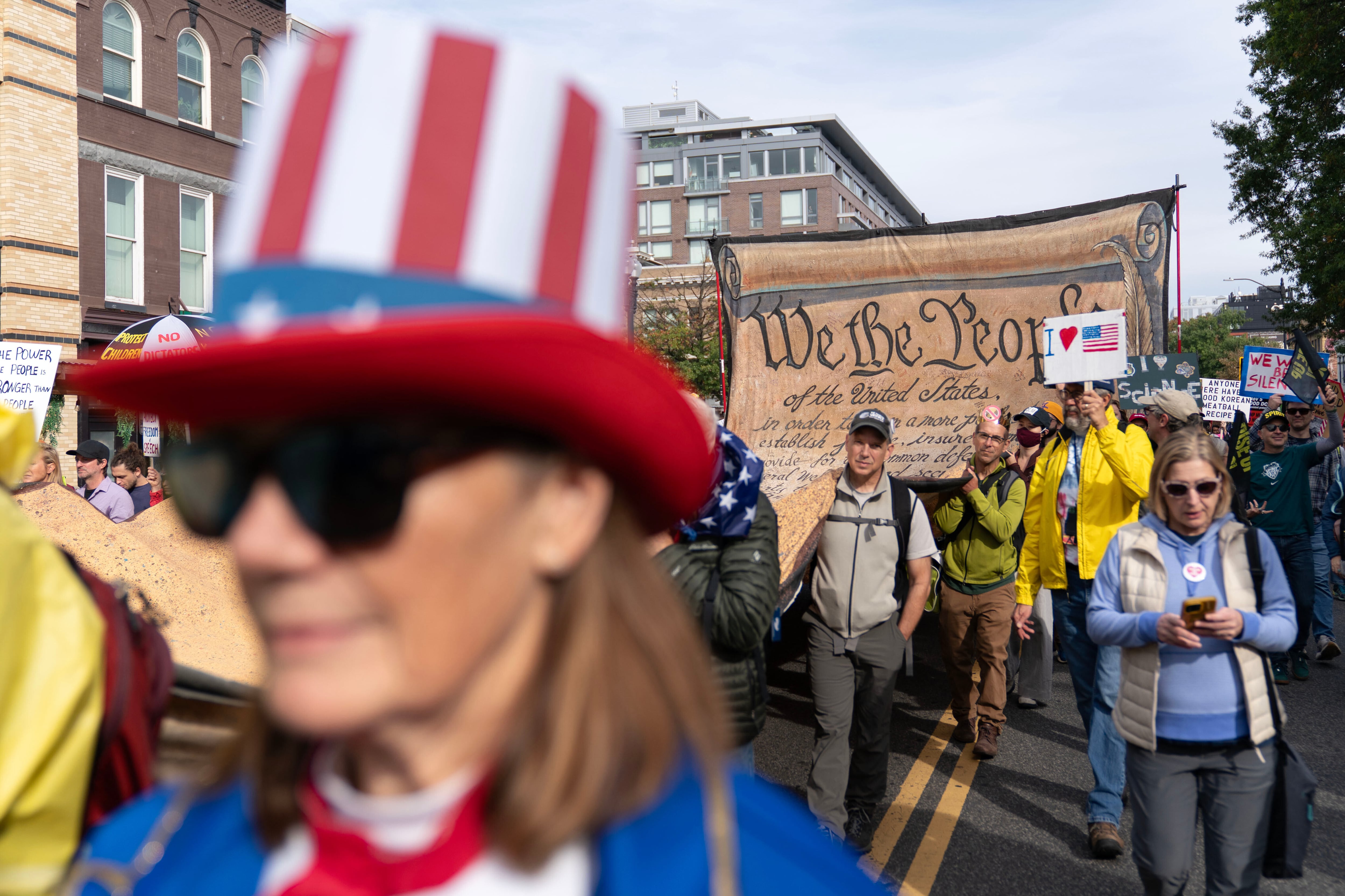 Manifestantes portan una pancarta firmada que representa la Constitución de Estados Unidos mientras marchan hacia el National Mall durante una protesta contra los "No Kings" en Washington.