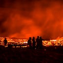 La gente observa cómo fluye lava de la erupción de un volcán en la península de Reykjanes en el suroeste de Islandia. La última erupción volcánica de Islandia atrae rápidamente a multitudes de personas que esperan acercarse a los suaves flujos de lava. Foto: AP / Marco Di Marco.