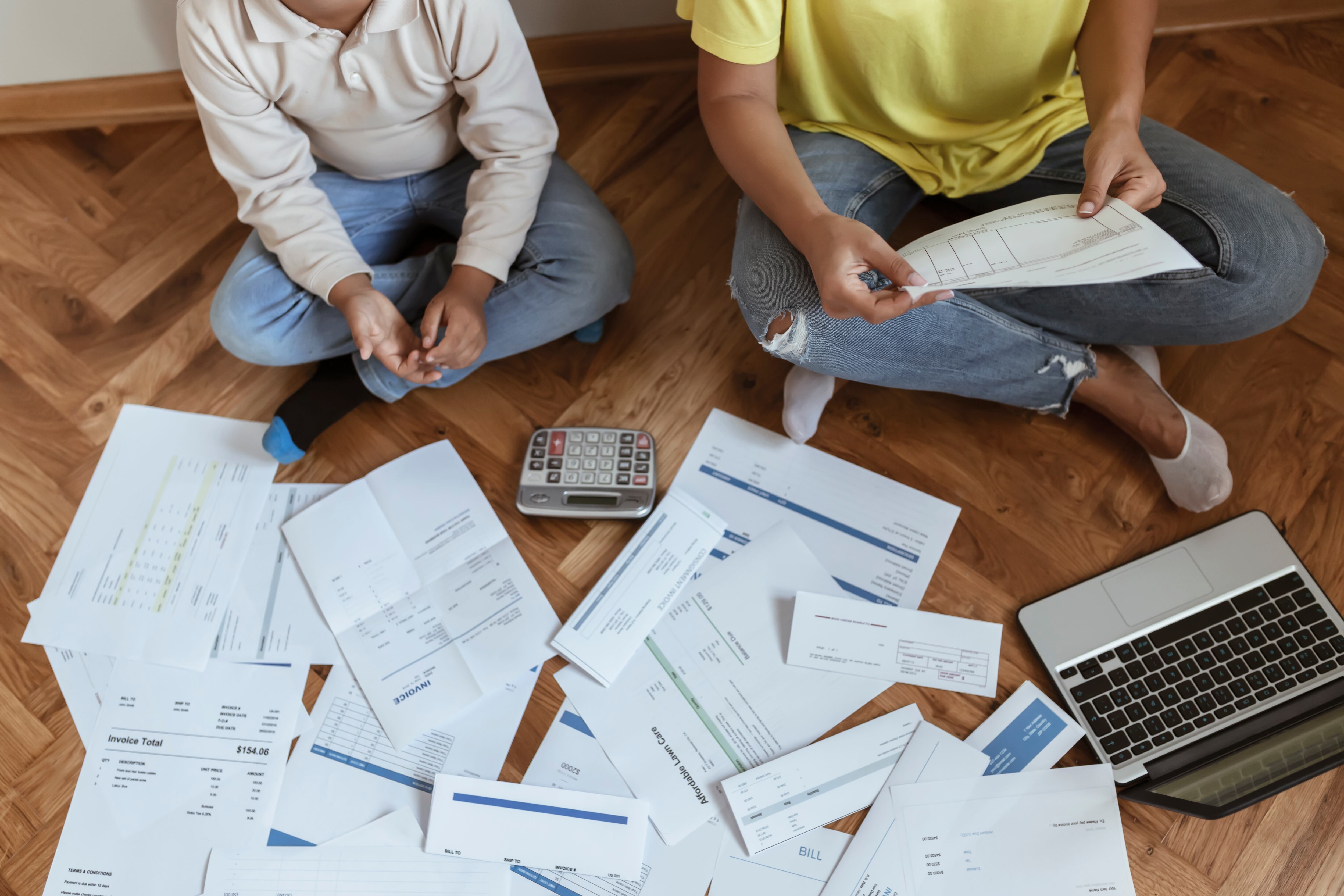 Mother and Son Sitting on the Floor at Home Checking Unpaid Bills, Taxes, Due Debt, Bank Account Balance. Mom Going Through Bills With Her Son. Single Mother Managing the Debt
