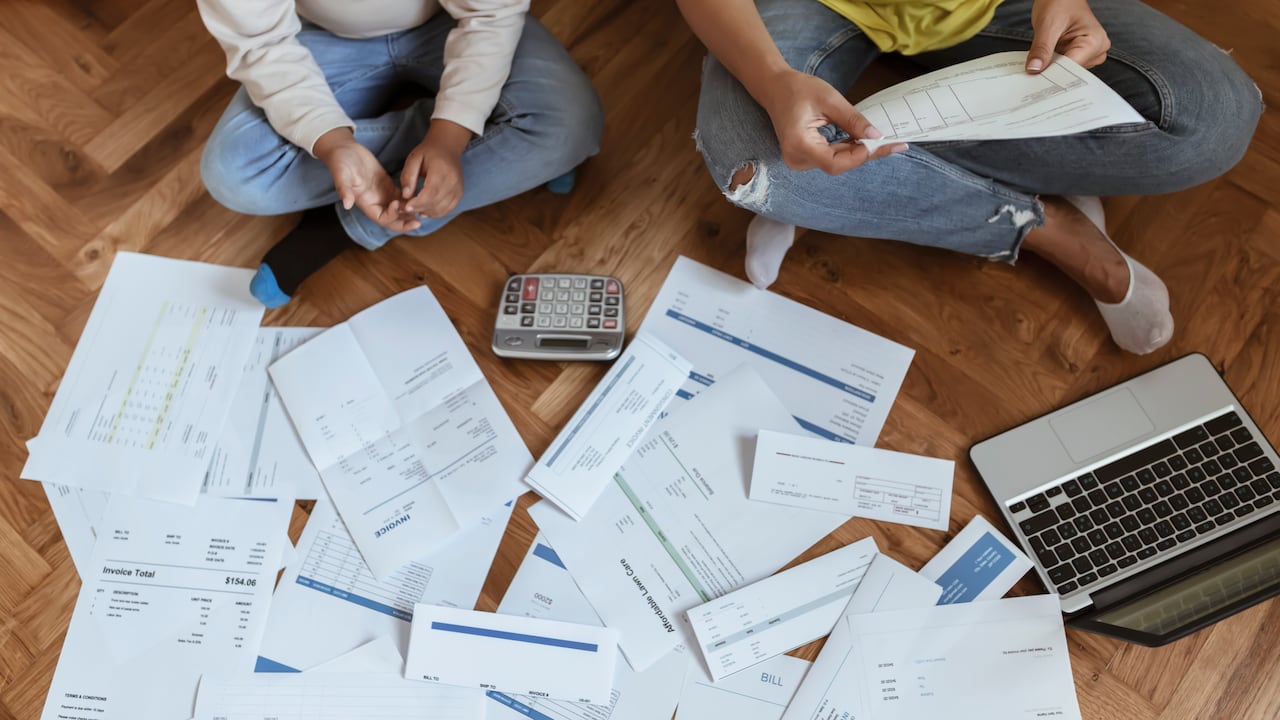 Mother and Son Sitting on the Floor at Home Checking Unpaid Bills, Taxes, Due Debt, Bank Account Balance. Mom Going Through Bills With Her Son. Single Mother Managing the Debt