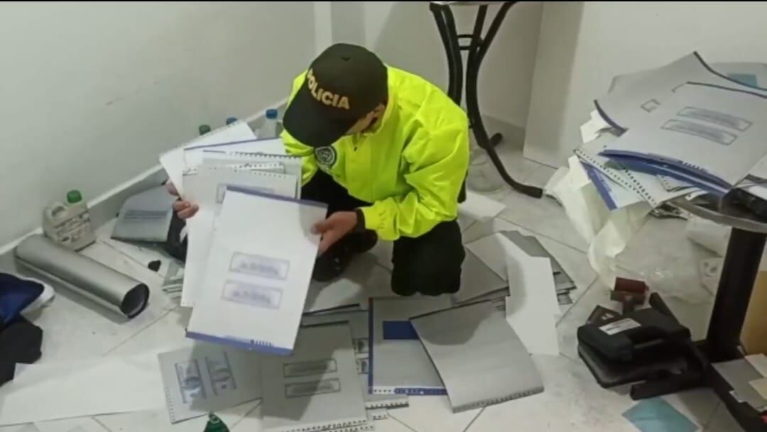 El policías sostiene las planchas que servían como molde de los dólares falsos.