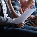 Cierra a jóvenes multirraciales irreconocibles sentados en fila en un sofá con documentos en papel o aparatos tecnológicos modernos, esperando una entrevista de trabajo o un examen, el concepto de reclutamiento de recursos humanos.