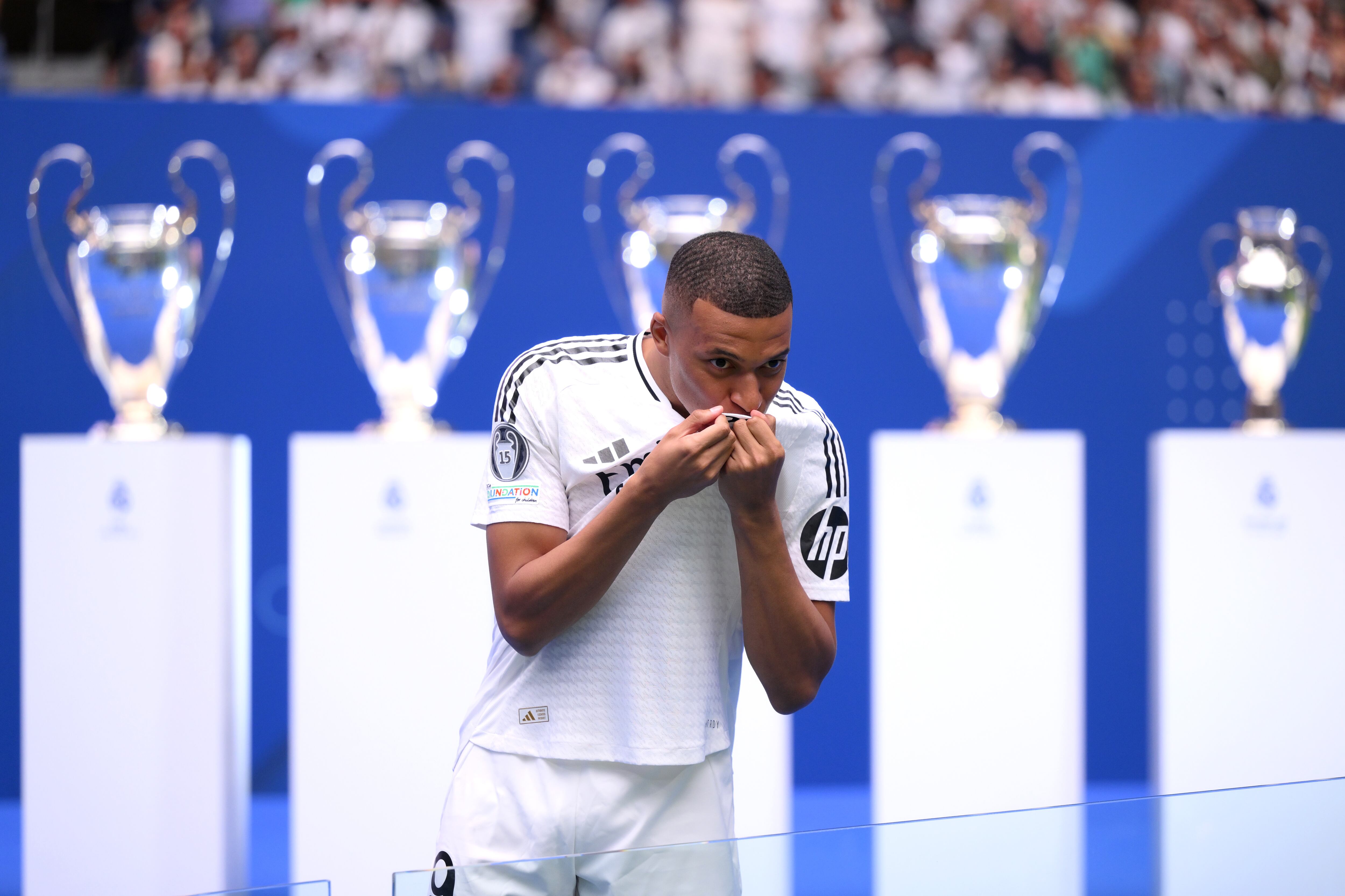 MADRID, SPAIN - JULY 16: Real Madrid new signing, Kylian Mbappe kisses the Real Madrid badge as he is unveiled at Estadio Santiago Bernabeu on July 16, 2024 in Madrid, Spain. (Photo by David Ramos/Getty Images)